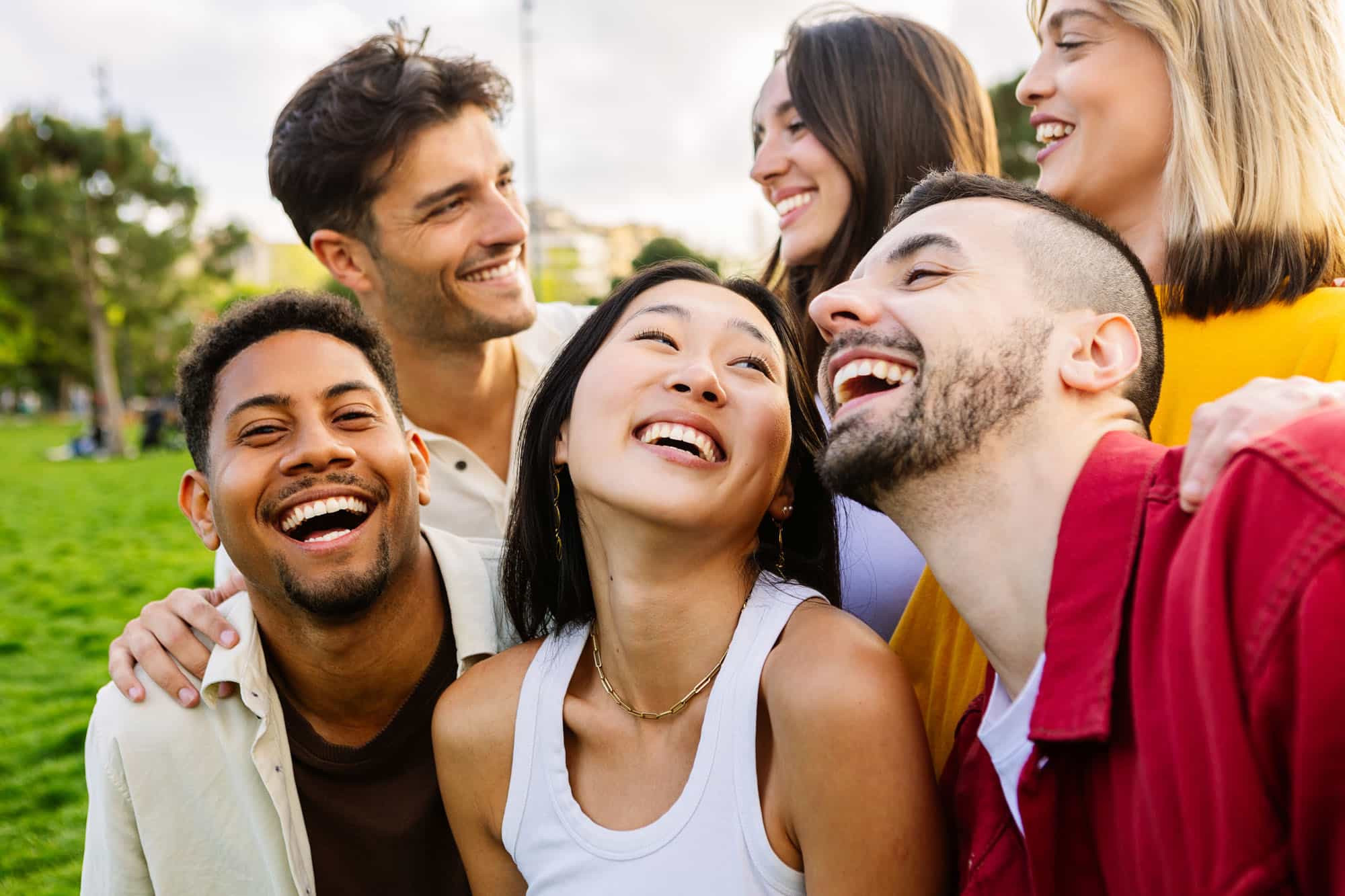 Diverse group of young friends having fun together outdoors in summer. Millennial student people laughing walking in city street enjoying holiday.